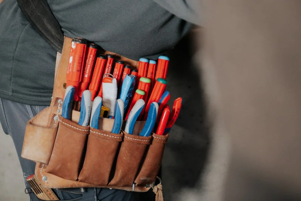 Person mit Arbeitstool-Gürtel voller rote, blaue und grüne Markierungsstifte