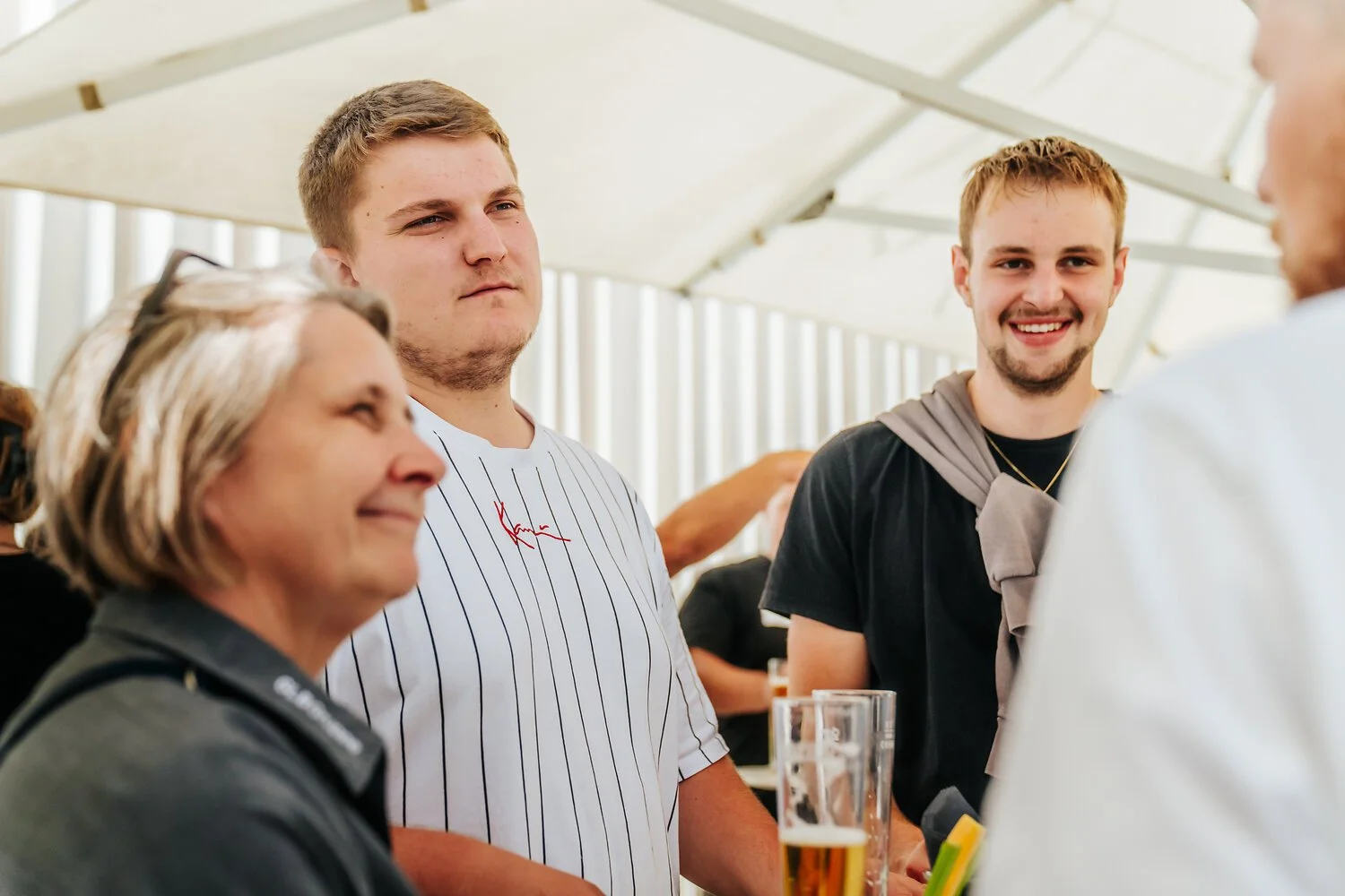 Menschen, die an einer Bar oder einem zeltartigen Dach sitzen, trinken Bier und unterhalten sich.
