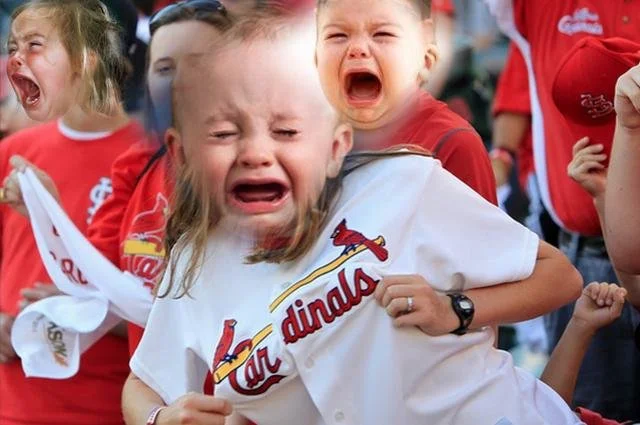 Children crying and upset, wearing St. Louis Cardinals baseball jerseys at a sporting event.