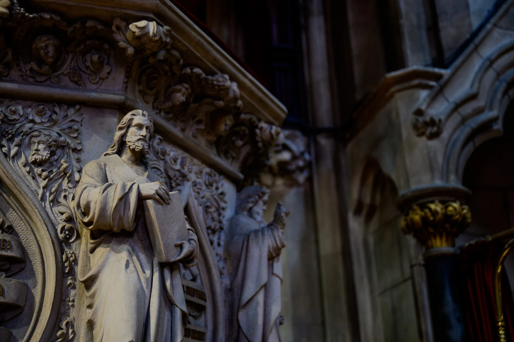 Close-up of intricate stone carvings on a historic building, featuring statues of Jesus Christ and decorative floral patterns.