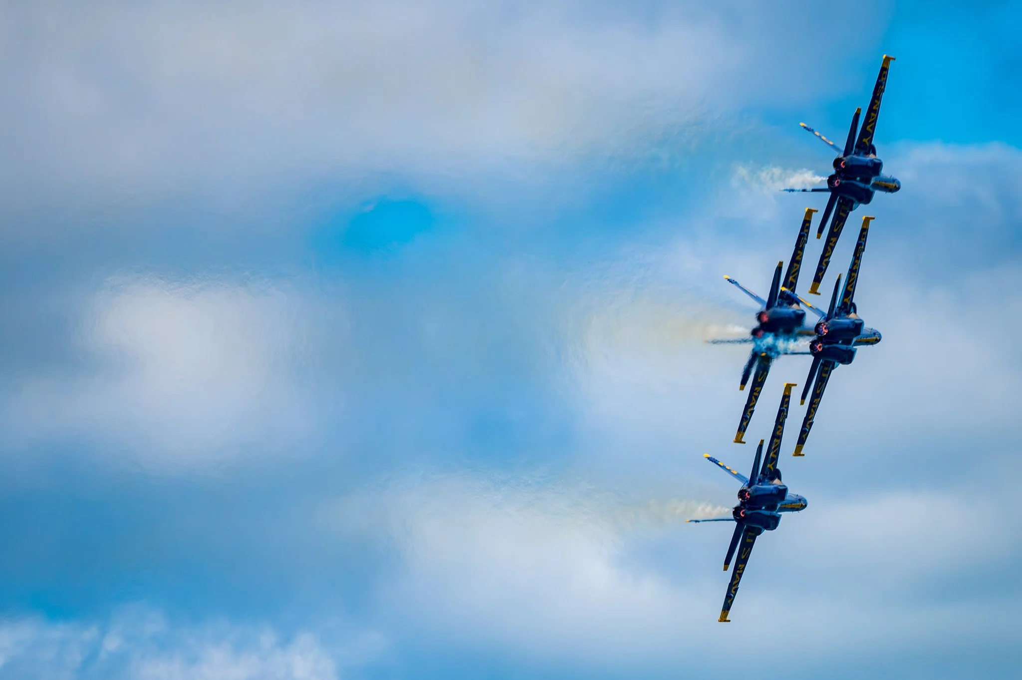 Fighter jets flying in formation through a cloudy sky, leaving smoke trails behind.
