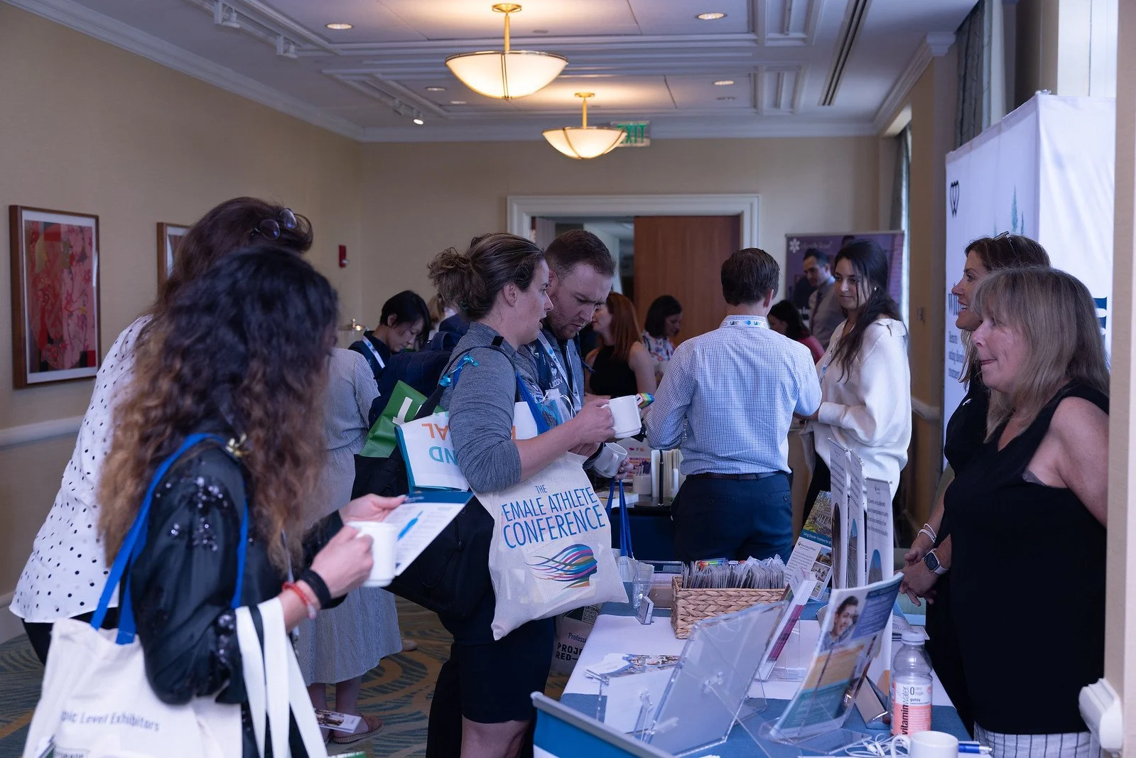 Attendees at a conference registration desk listening to a representative.