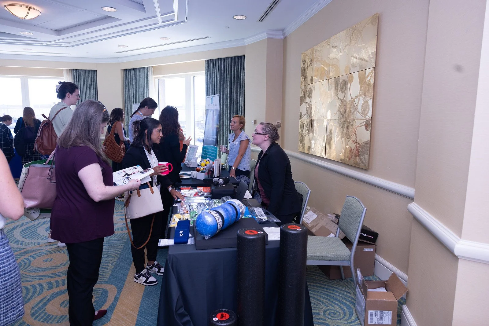 People attending a conference or trade show at a registration or exhibitor booth in a hotel conference room.