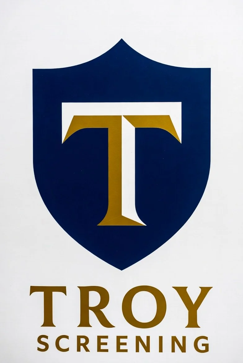 Logo for Troy Screening featuring a shield with a stylized letter 'T' in the center, all in gold and navy blue on a white background.