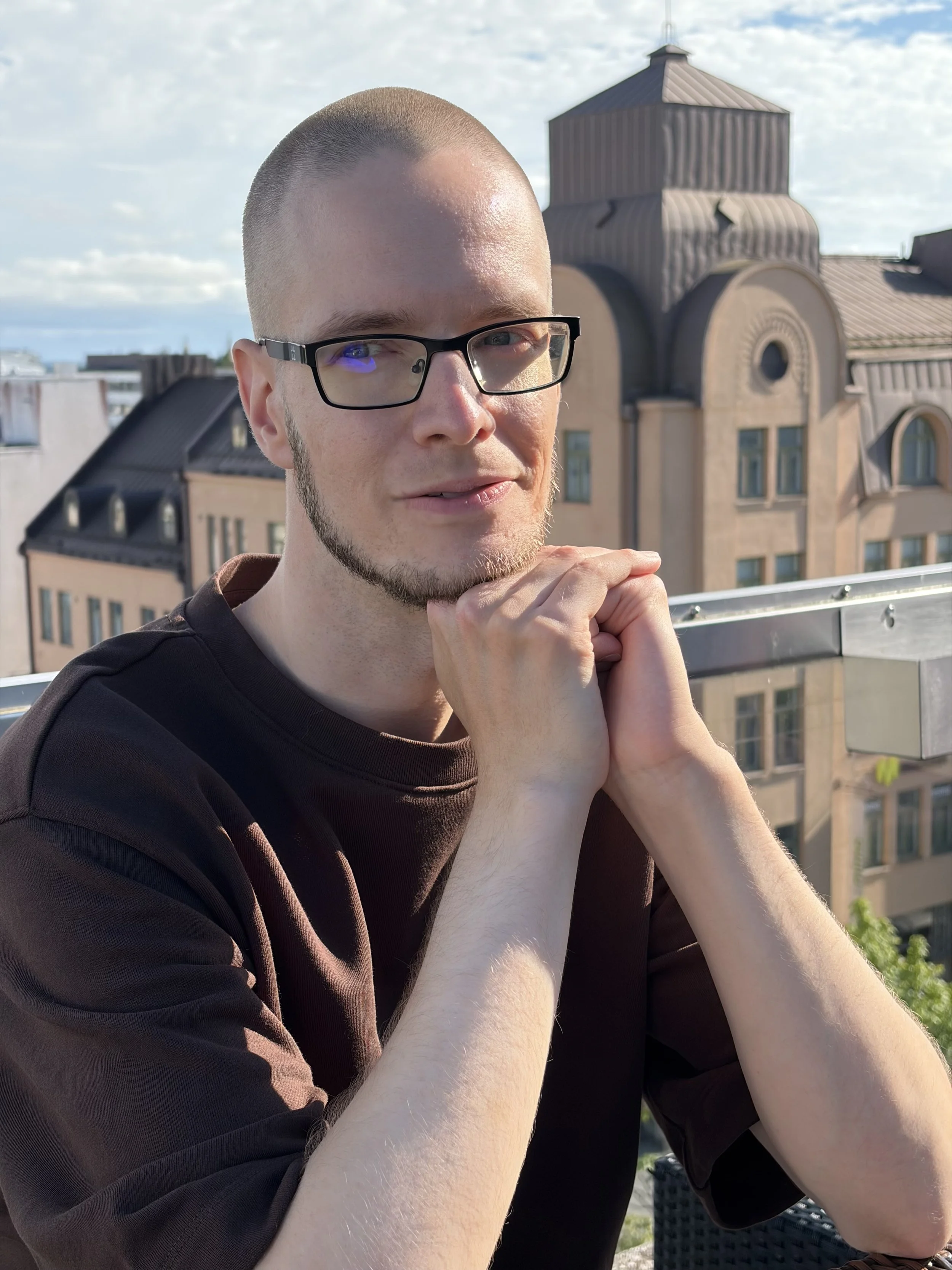 Antti Raatikainen istuu terassilla kädet yhdessä ja katsoo kamerasta sivuun.