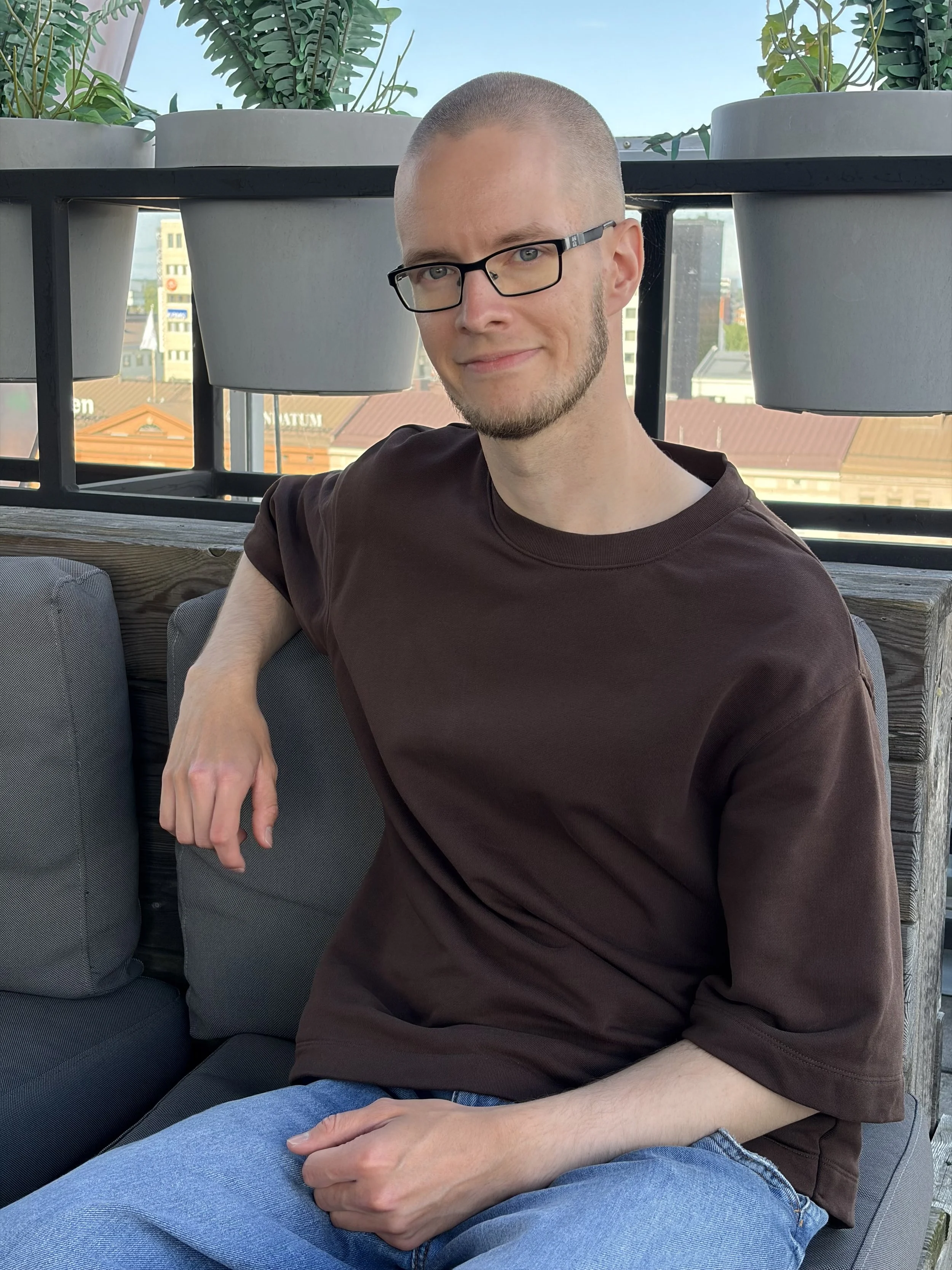 Antti Raatikainen istuu ulkona terassilla rauhallisesti hymyillen.
