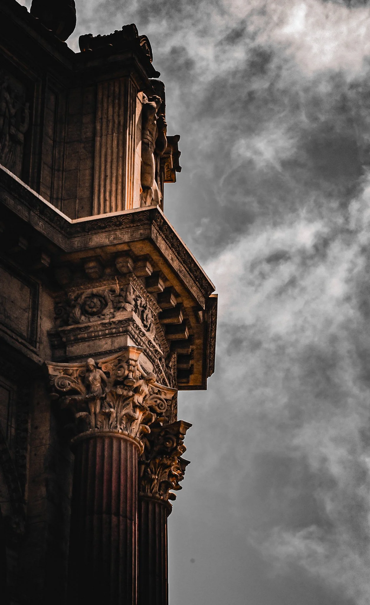 Close-up of ornate classical architectural details on a building, with dark clouds in the background.