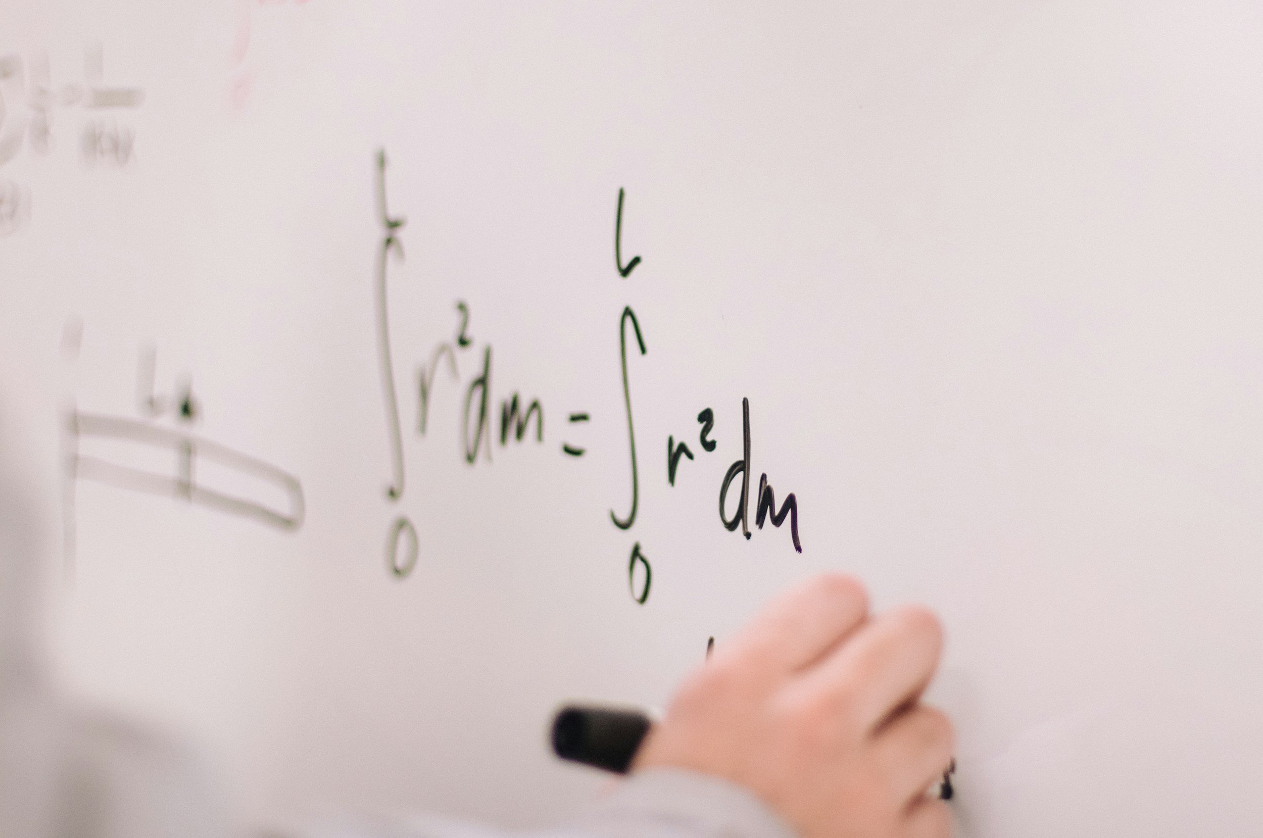 Hand writing an integral equation on a whiteboard, representing one-on-one Pre-Calculus tutoring over Zoom