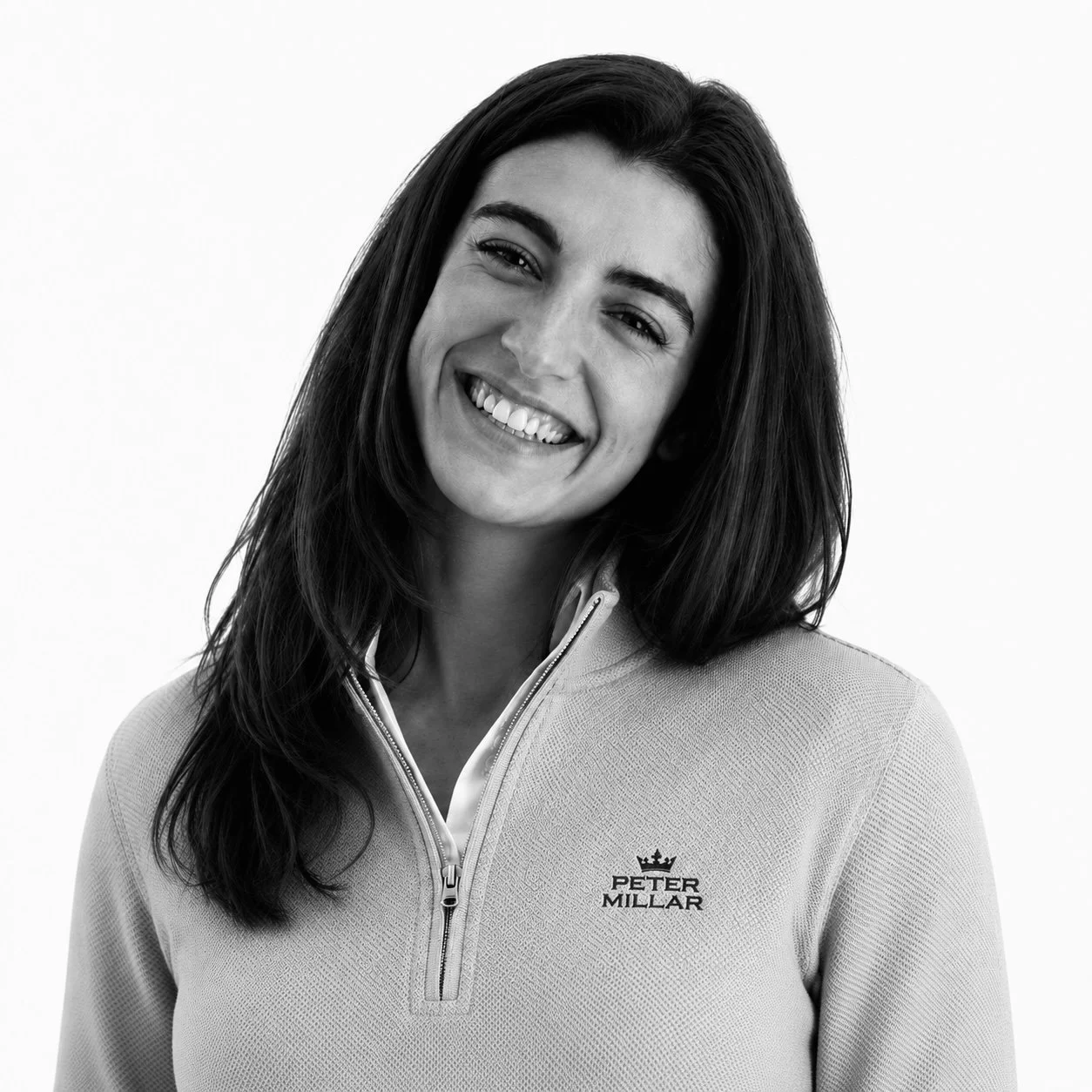 Beatrice, communications lead, Rêverie Golf team member smiling and wearing a white Peter Millar polo shirt, portrait on a white background.