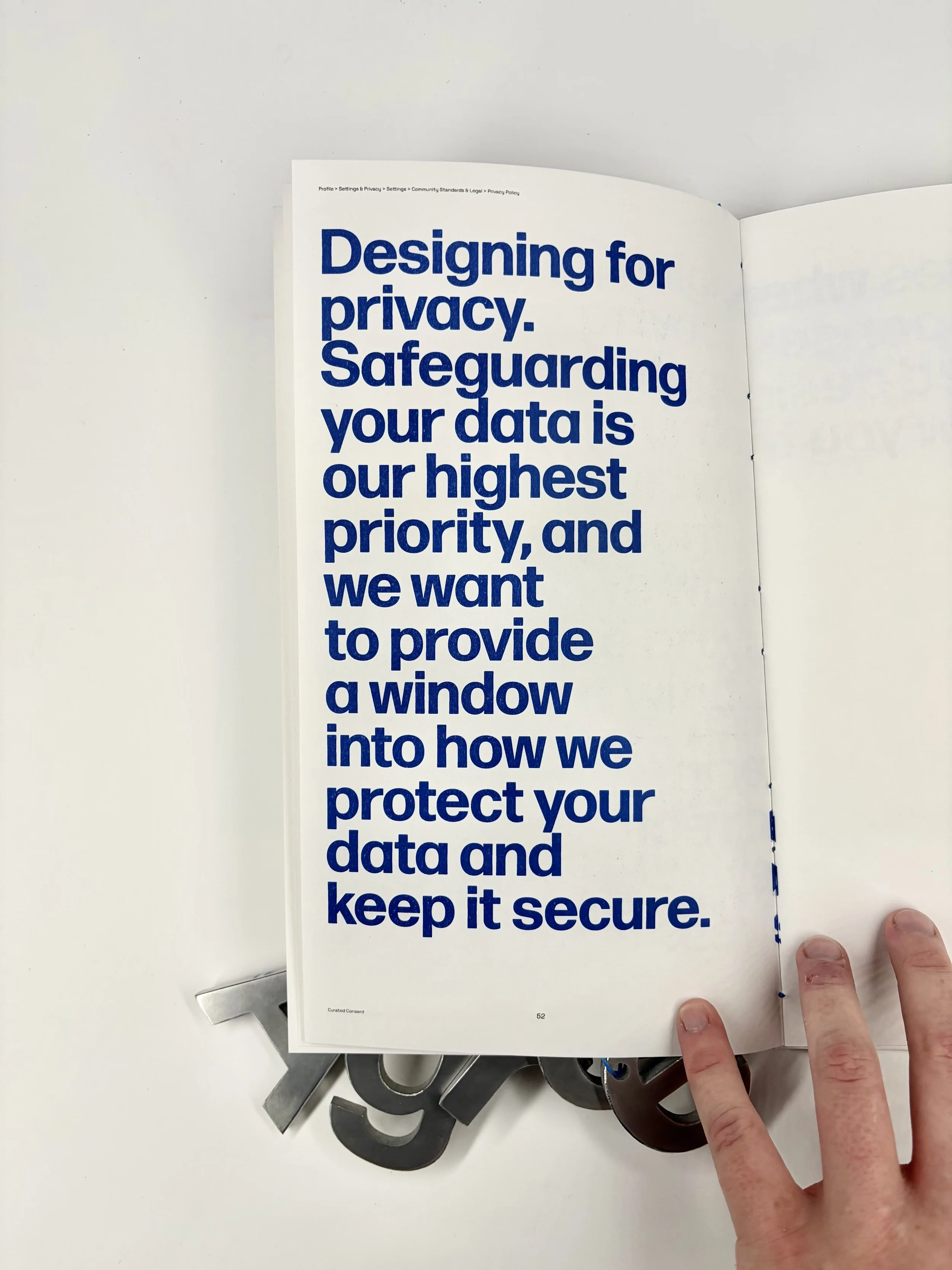 Open book with text about designing for privacy and data protection, held by a person's hand with fingers visible on the lower right.