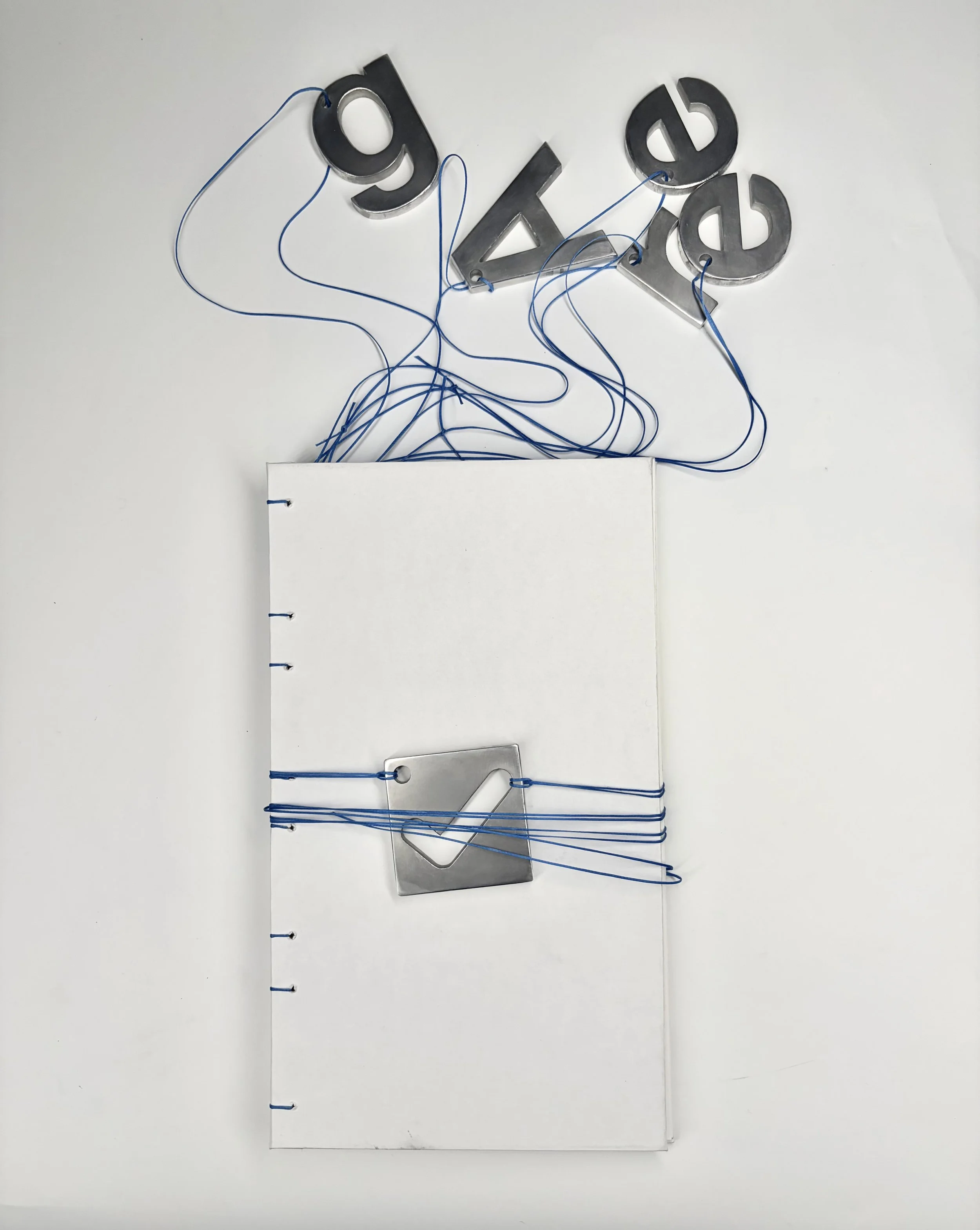 A white binder with blue rings open on a white surface, with a sheet of paper partially inside. Above, blue strings connected to metallic 3D letters.