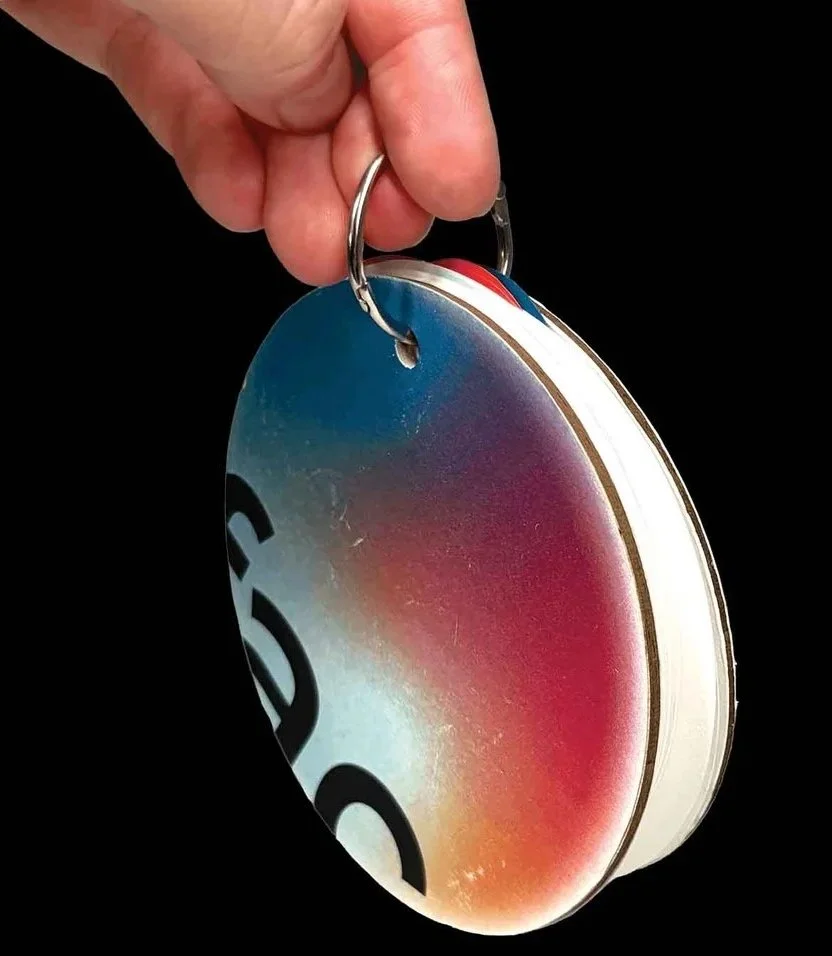 Hand holding a stack of circular discs with colorful gradient patterns on a black background.
