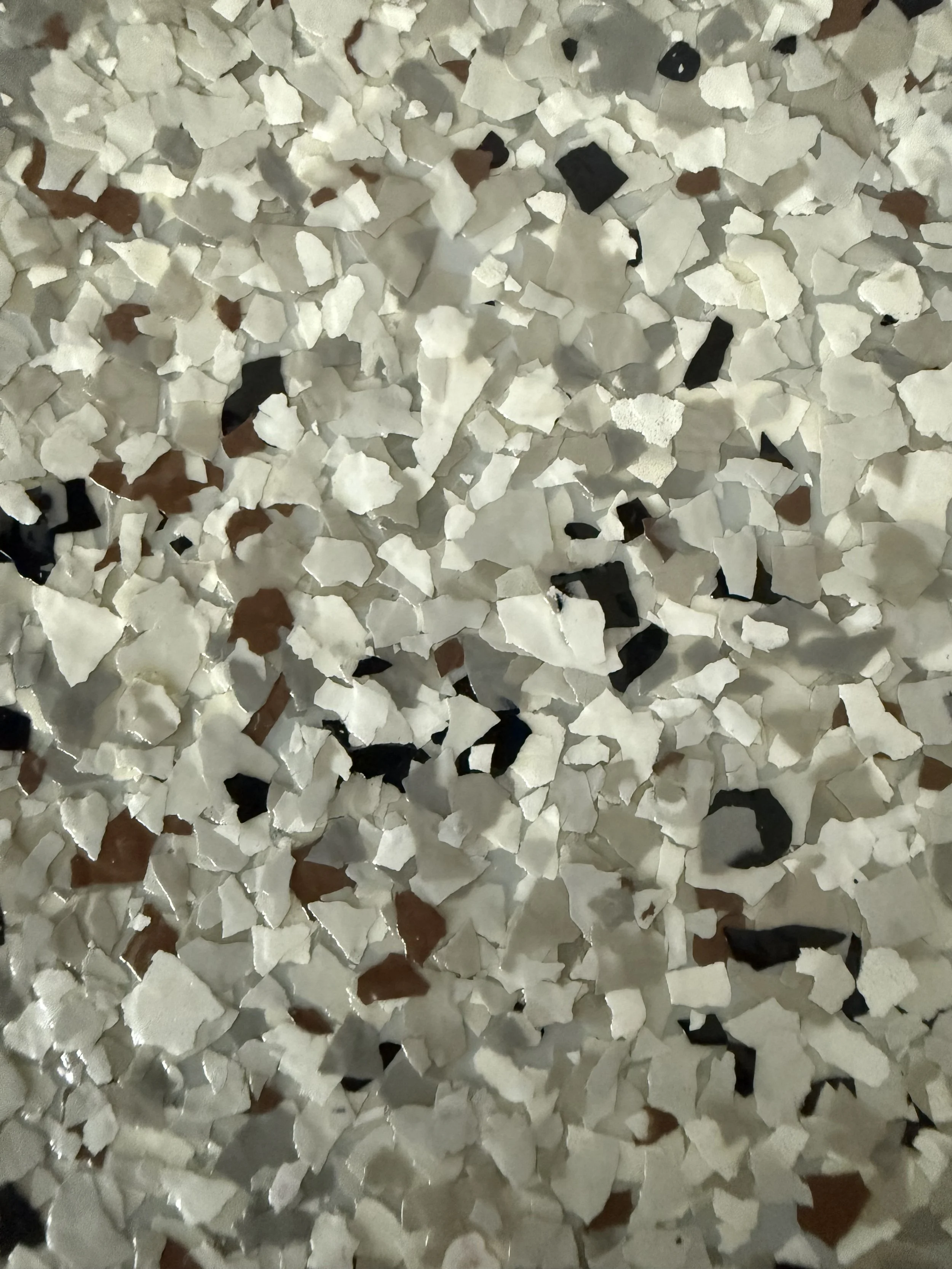 Close-up of broken white, black, and brown ceramic or porcelain pieces scattered on a surface.