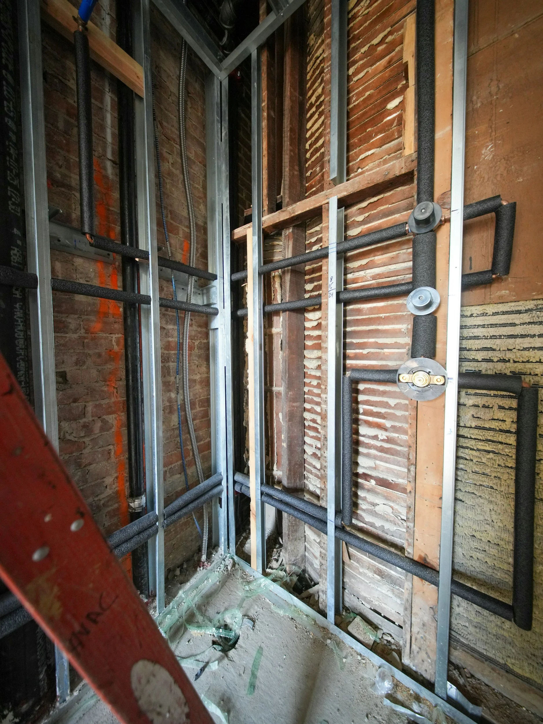Construction site showing metal framing and exposed brick wall in an unfinished building.