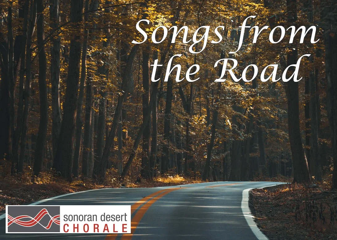 A winding road through a wooded forest with autumn leaves, overlaid with white text reading 'songs from the Road' and a logo for Sonoran Desert Chorale in the bottom left corner.