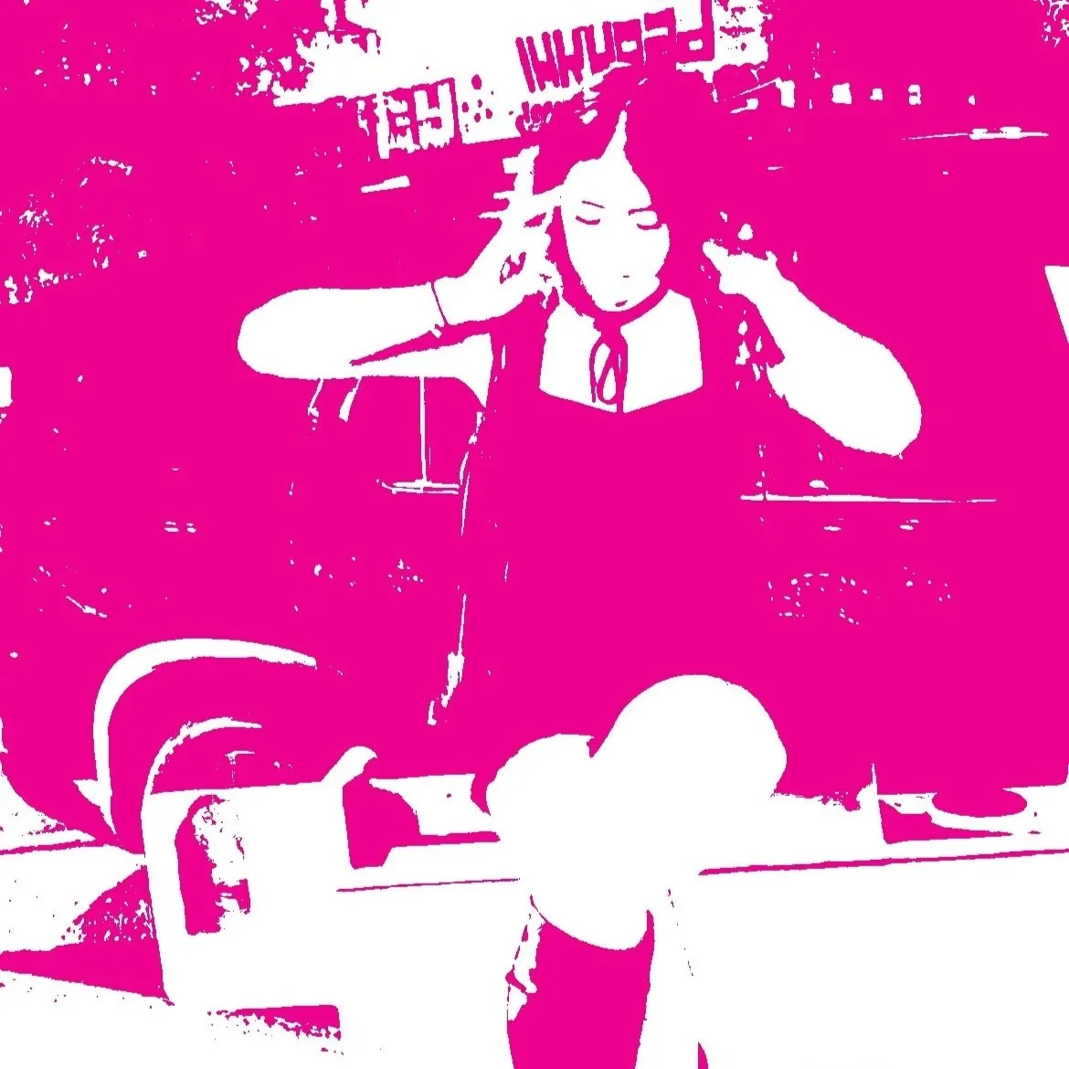 A person with long hair touching their ears in an outdoor setting, with pink and white color effects.