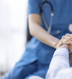 Close-up of a healthcare professional in blue scrubs holding a patient's hand.