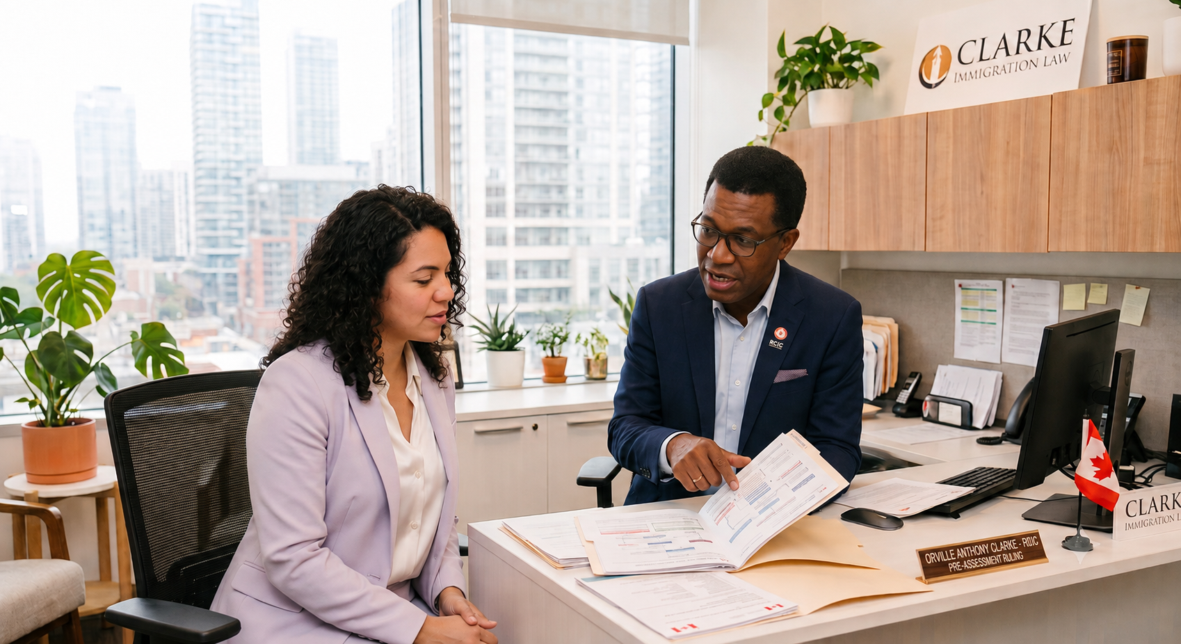 A man and woman sitting at a desk in an office, discussing documents. The man is pointing to paperwork, dressed in a navy suit, and the woman is wearing a light-colored blazer. Office supplies, potted plants, and a city skyline view are visible in the background.