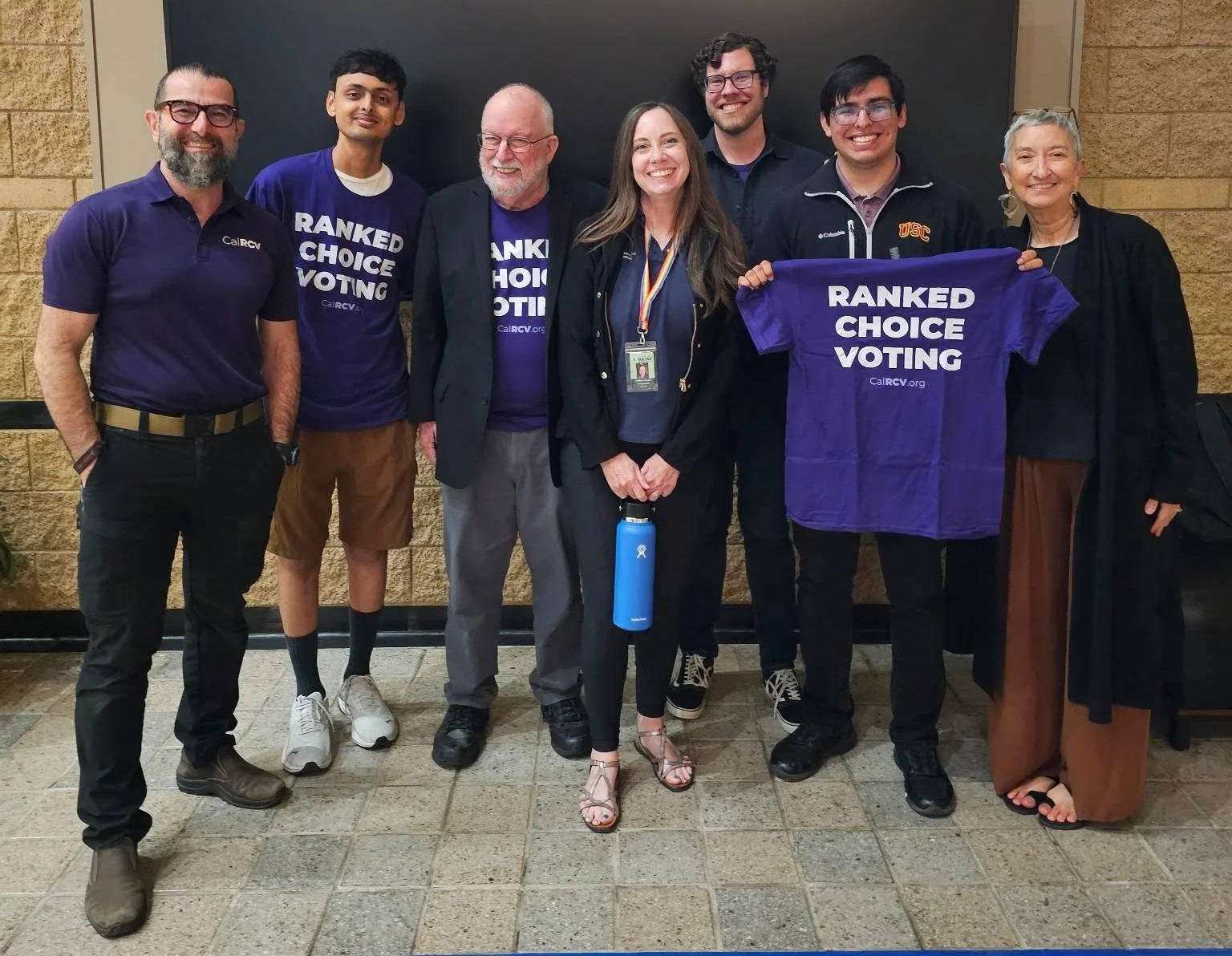 Arash Saydi, Mari Fujii, Councilmember Kathleen Treseder and many others stand together celebrating the City of Irvine directing City Staff to put ranked choice voting for municipal elections to the voters in November 2026. Vote YES on Measure D for