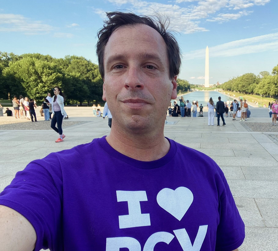 Jeremy takes a selfie at the National Mall in Washington, D.C., with the Washington Monument in the background, during daytime with clear skies, proudly wearing his I-heart-RCV tee. Vote YES on Measure D for RCV!