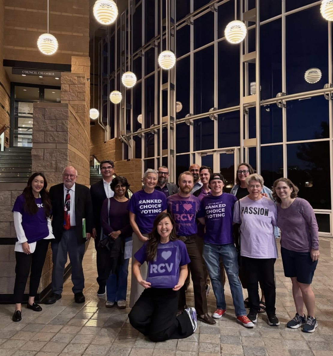 Branda Lin and various others stand together inside Irvine City Hall, many in shirts showing their support for ranked choice voting, smiling for a photo. Vote YES on Measure D for RCV!