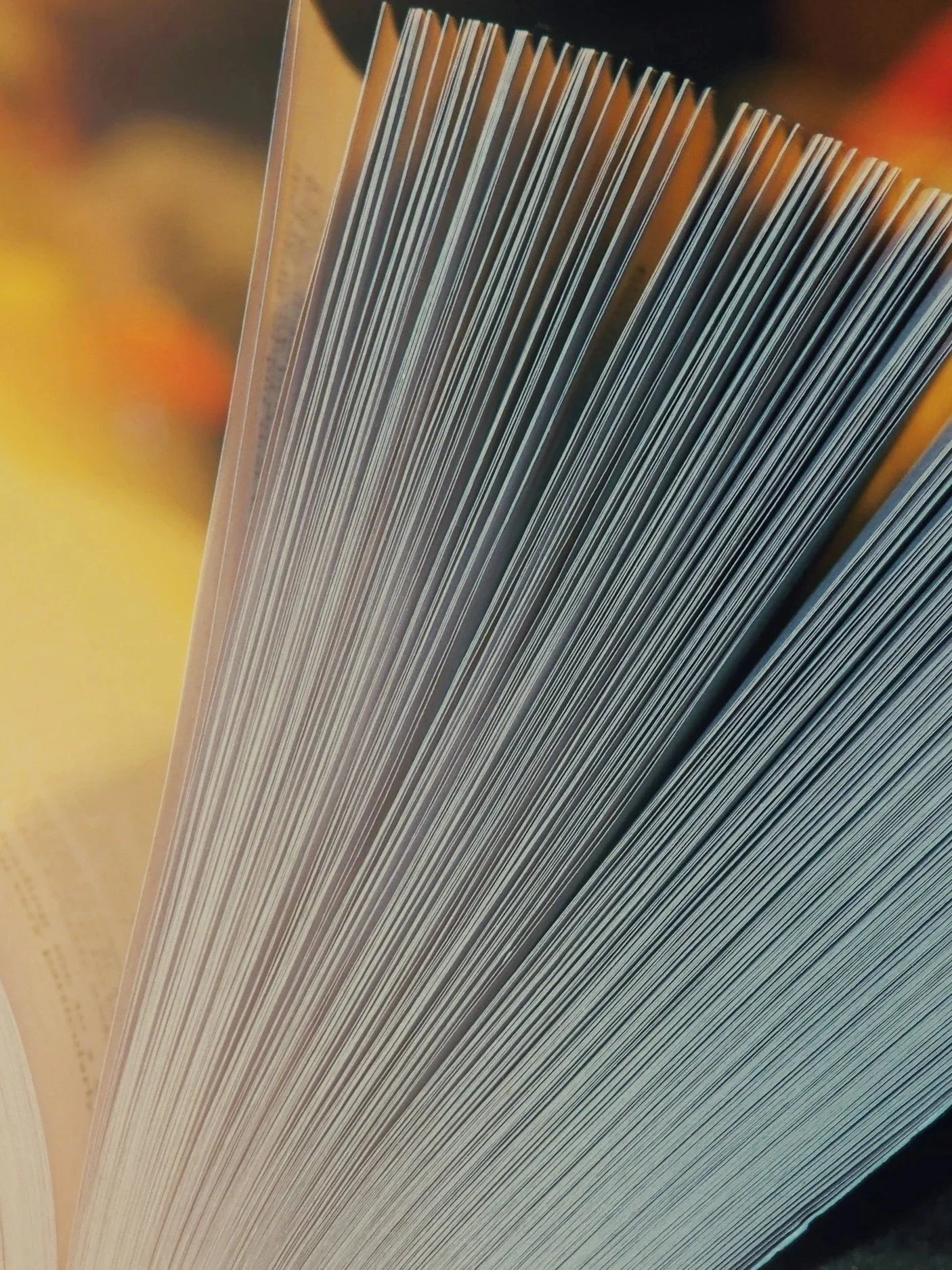 Close-up of a book's pages showing lines of text and a colorful yellow and orange background.