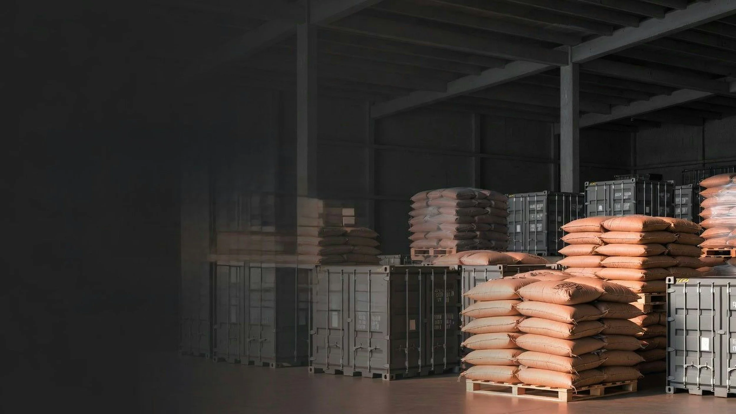 Stacks of orange bags filled with materials, placed on wooden pallets in an industrial warehouse setting.