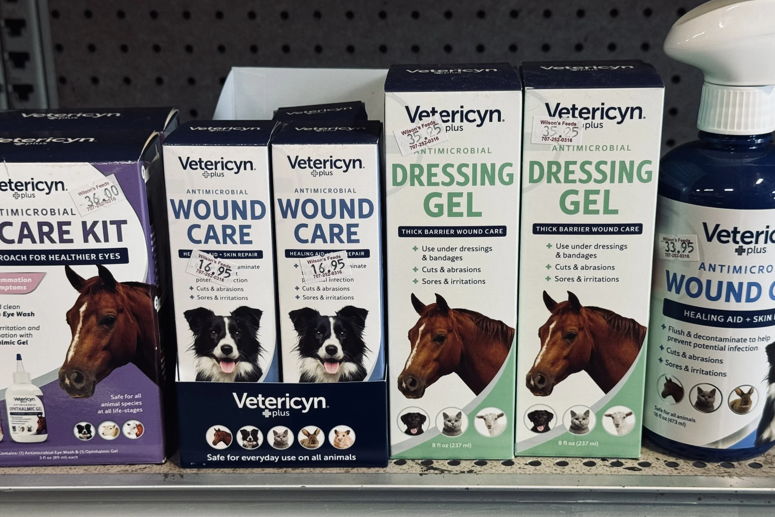 Shelf of veterinary wound care products, including antimicrobial gels and kits, with packaging showing images of various animals like dogs, cats, and horses.