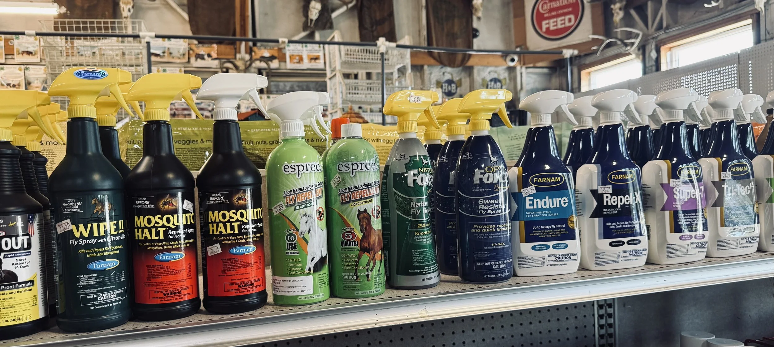 A store shelf displaying various insect and pest control spray bottles, including brands like Farnam, Espree, Natural Fury, Opti-Flex, Endure, Repel-X, Super 7, and TriTec.