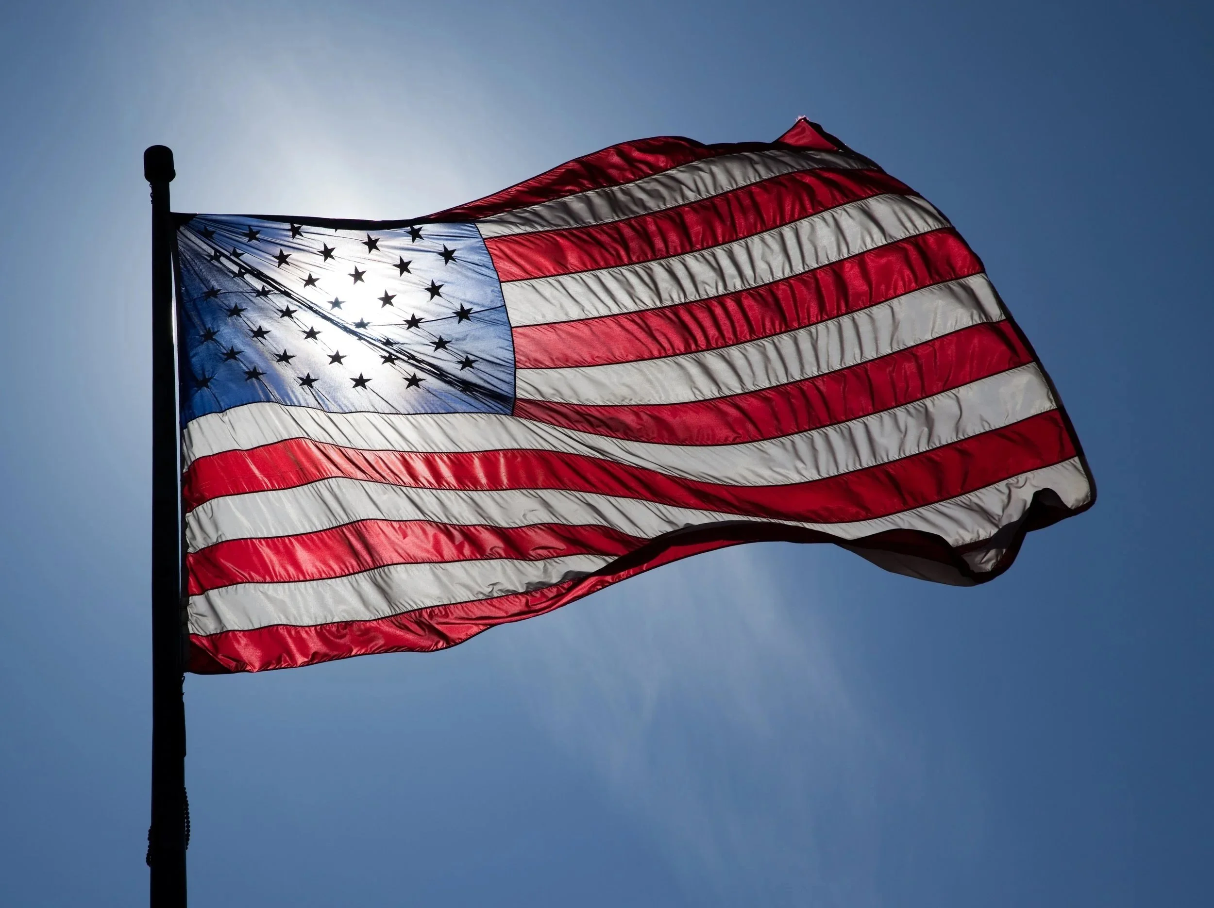 An American flag waving in the wind against a clear blue sky.