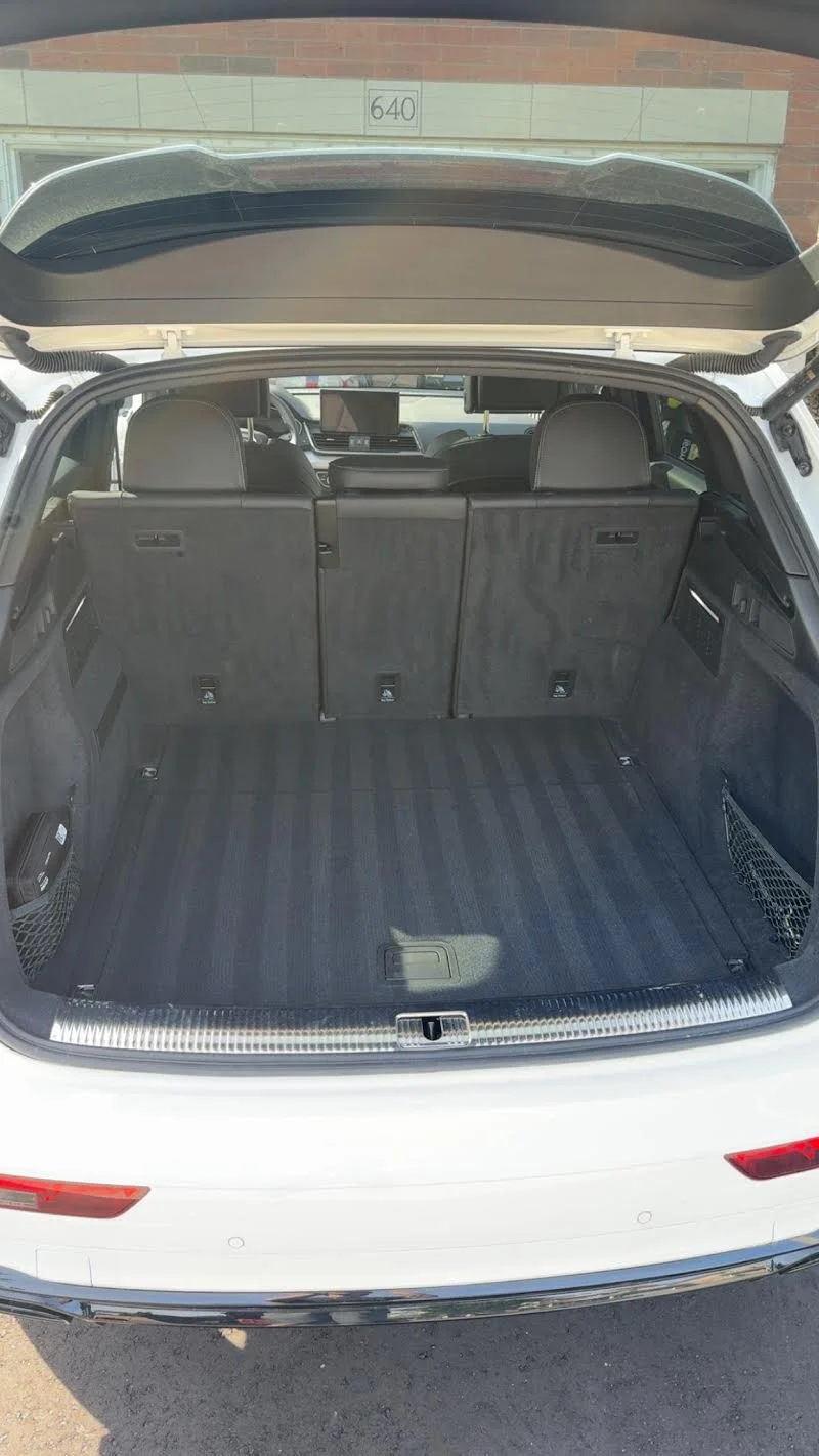 Open trunk of a white SUV showing a spacious cargo area with rear seats in upright position.