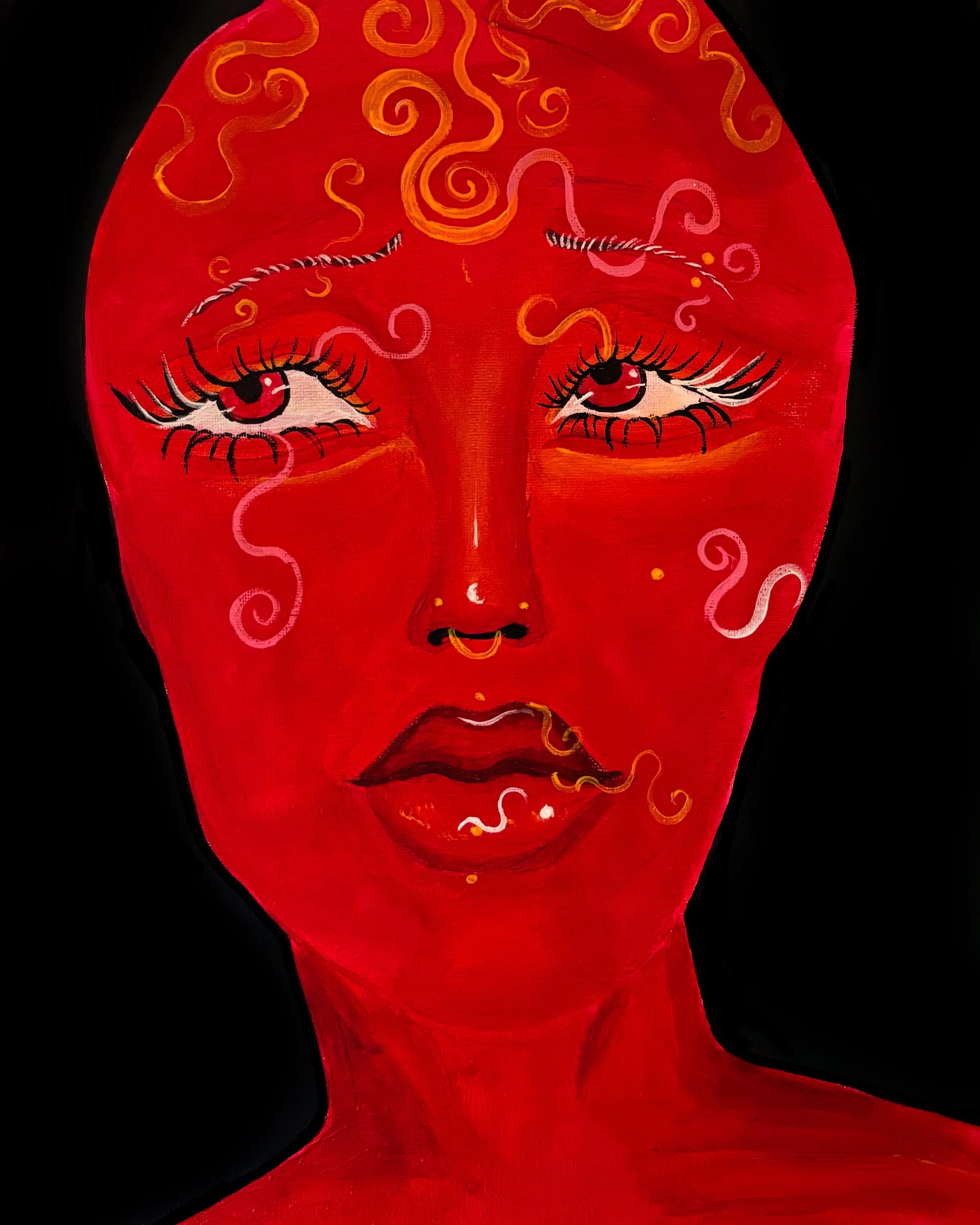 A red face mask with a painted face featuring large eyes with exaggerated eyelashes, a small nose, and a closed mouth. The mask has swirling patterns in orange and pink on the forehead and cheeks, and a black stripe running across the top.
