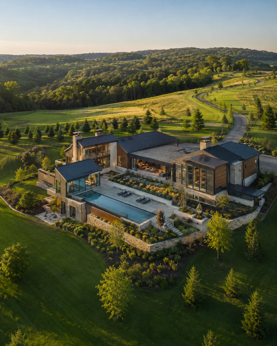 Aerial view of a modern residential property in rolling green terrain.