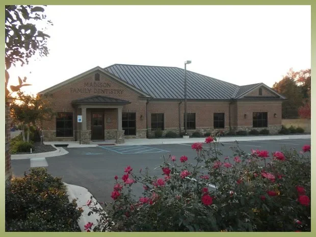 Exterior view of Madison Family Dentistry building with a parking lot and pink flowers in the foreground.