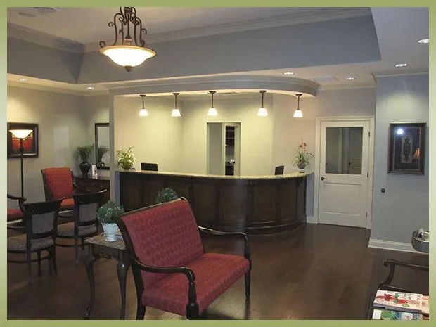 Hotel lobby reception area with a curved desk, seating chairs, and decorative plants.