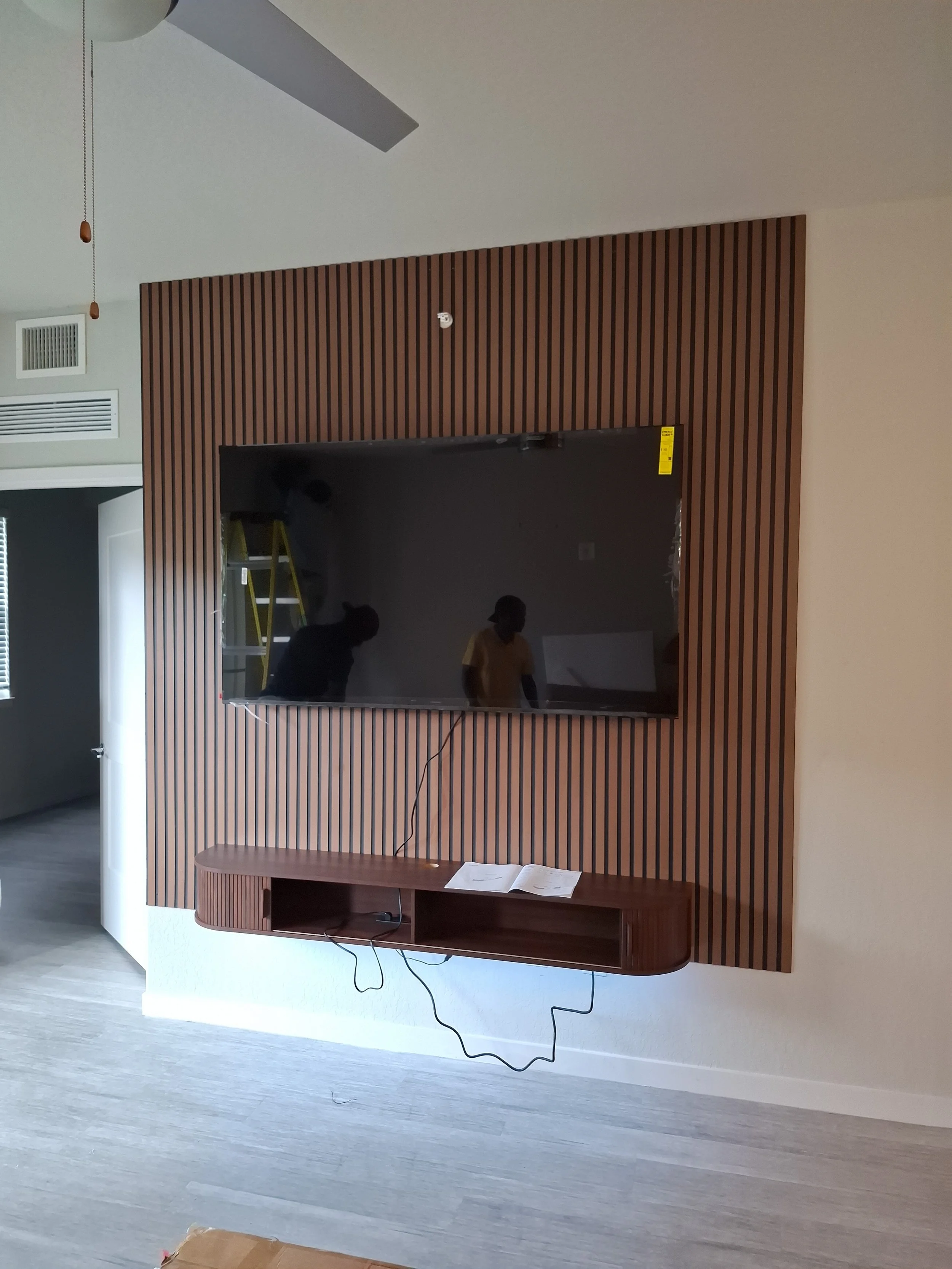 Wood slat accent wall with a mounted TV and floating console installed by CBX
