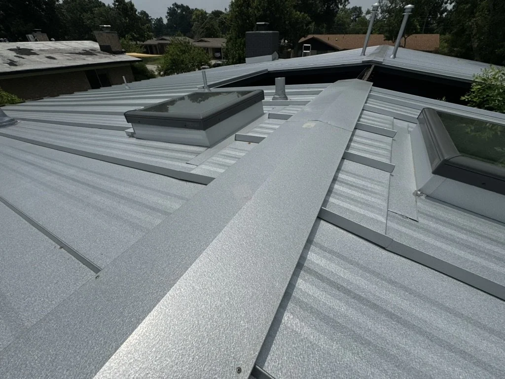 Metal roof with ventilation and skylights in a residential neighborhood.