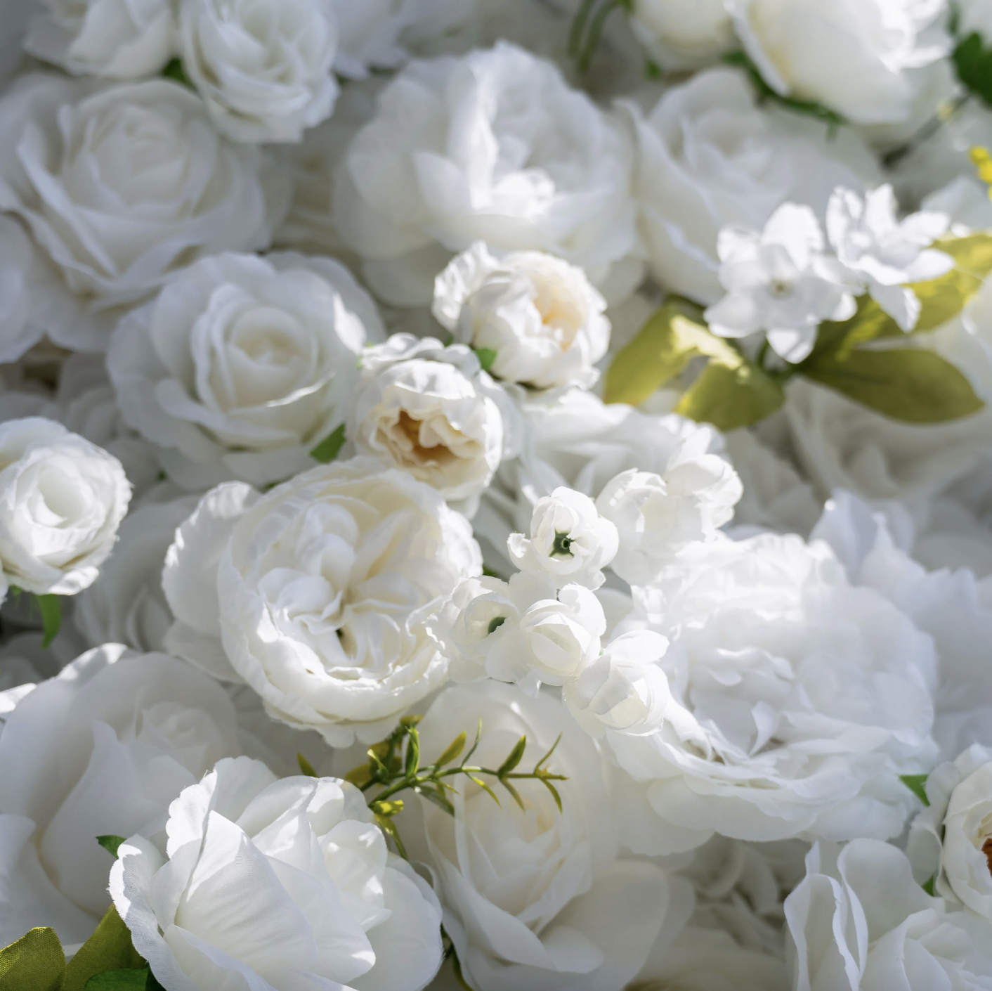 A close-up of a floral arrangement with white roses, white hydrangeas, and other white flowers.