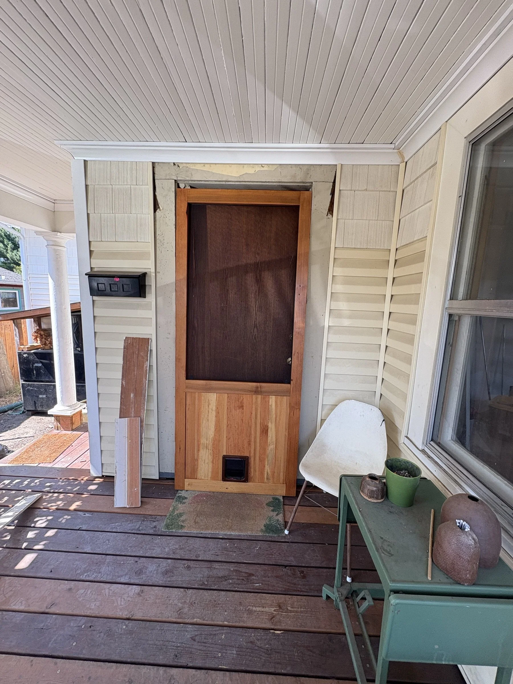 A custom wood screen door being installed on a porch.