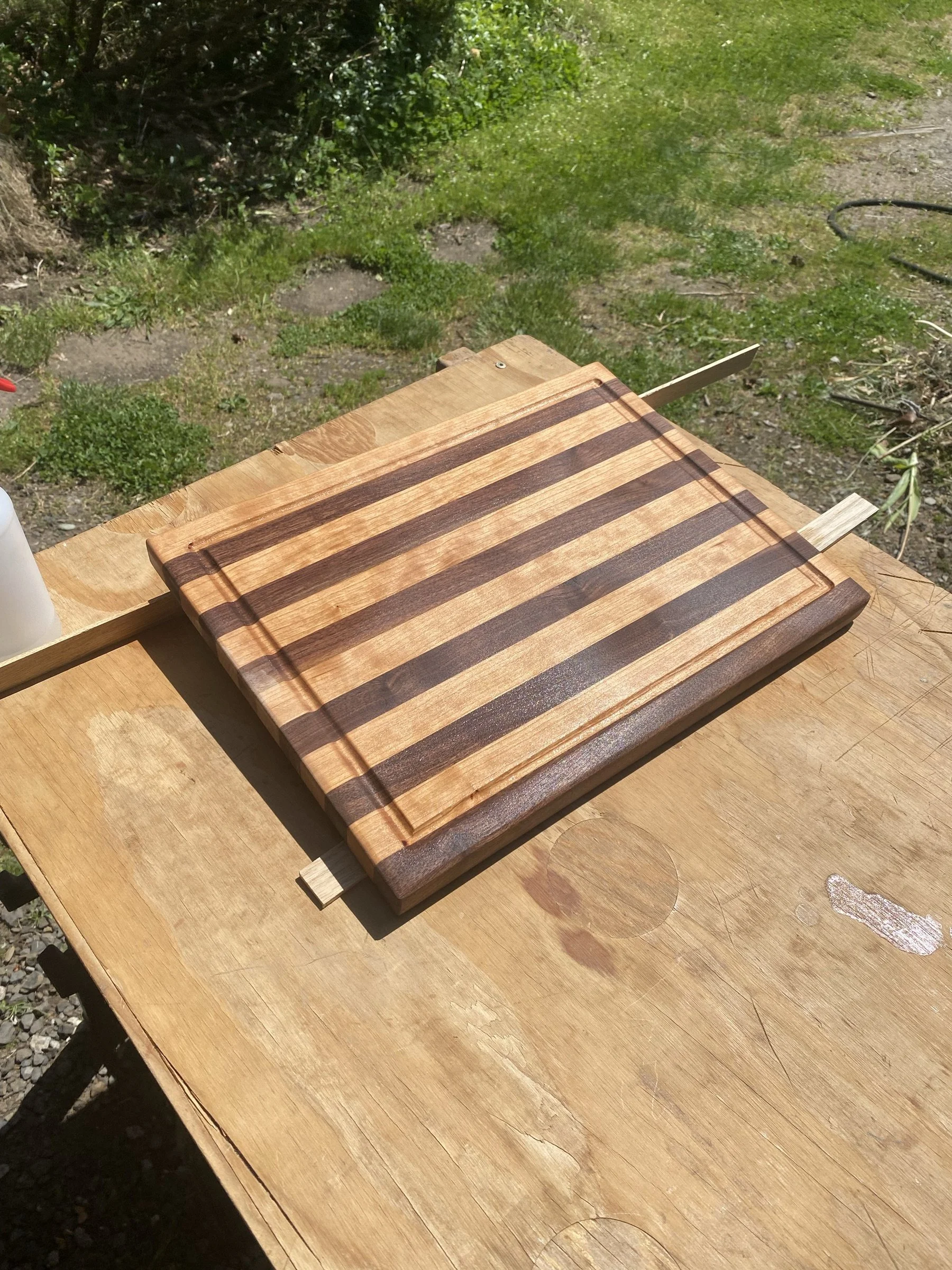 A cutting board resting on plywood in a yard.