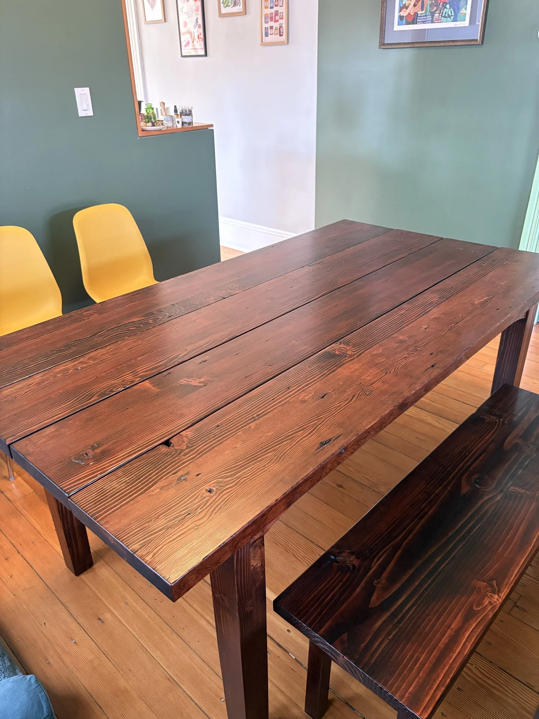 Farmhouse dining table and bench with yellow chairs in a bright room.
