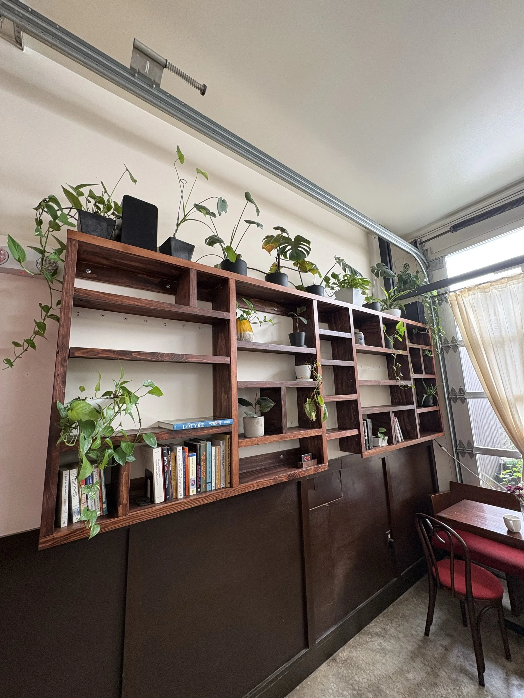 The plant-filled 11-foot community bookshelf at Fressen, seen at an angle.