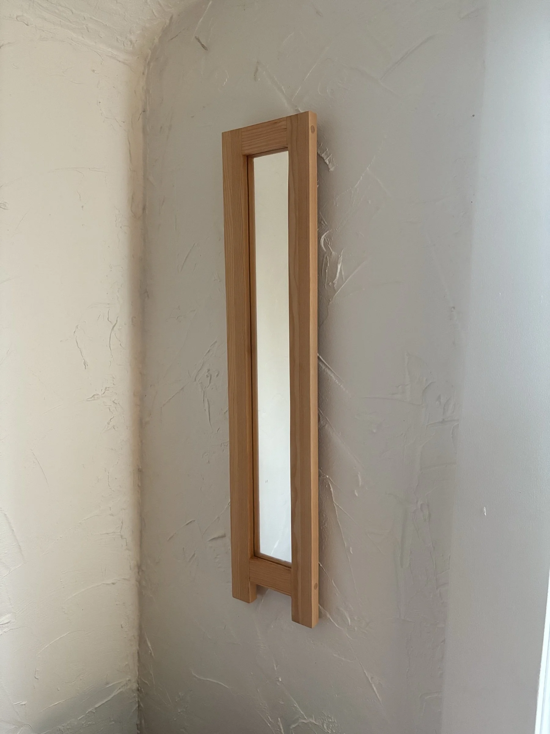 A single tall mirror framed in reclaimed fir.
