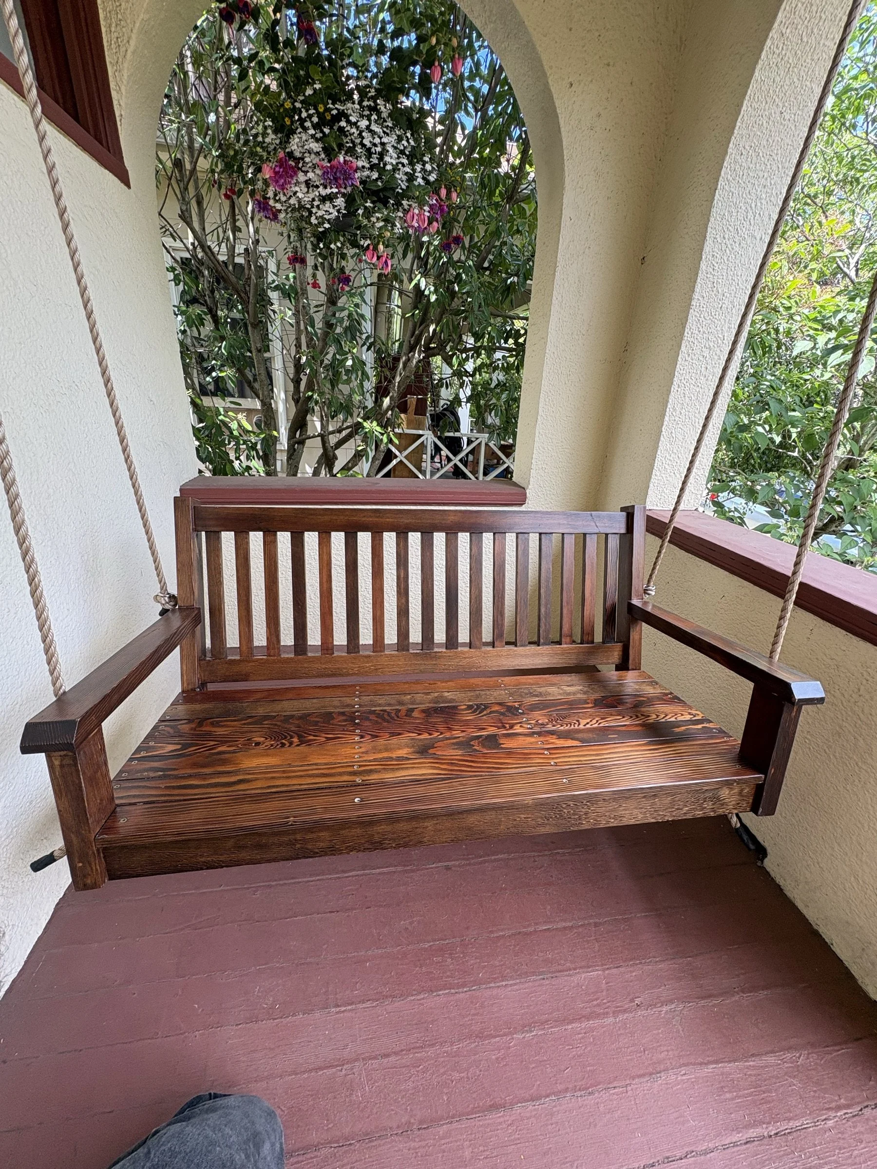 Straight-on view of the porch swing hung in the arched porch opening.