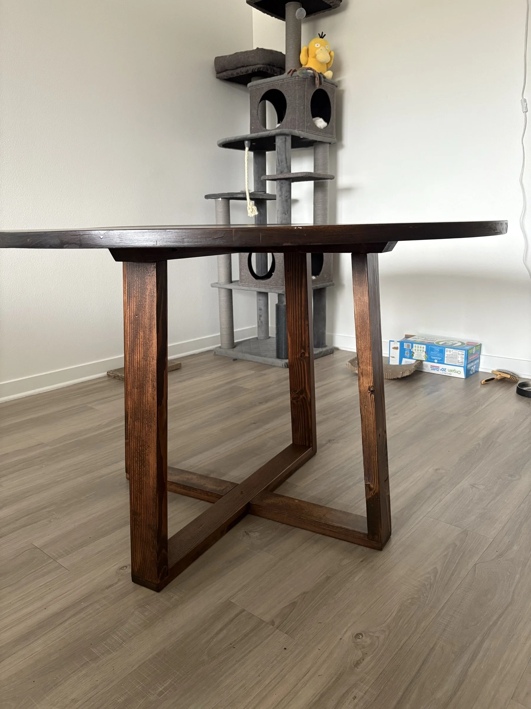 A round table with visible X-base legs in a kitchen.