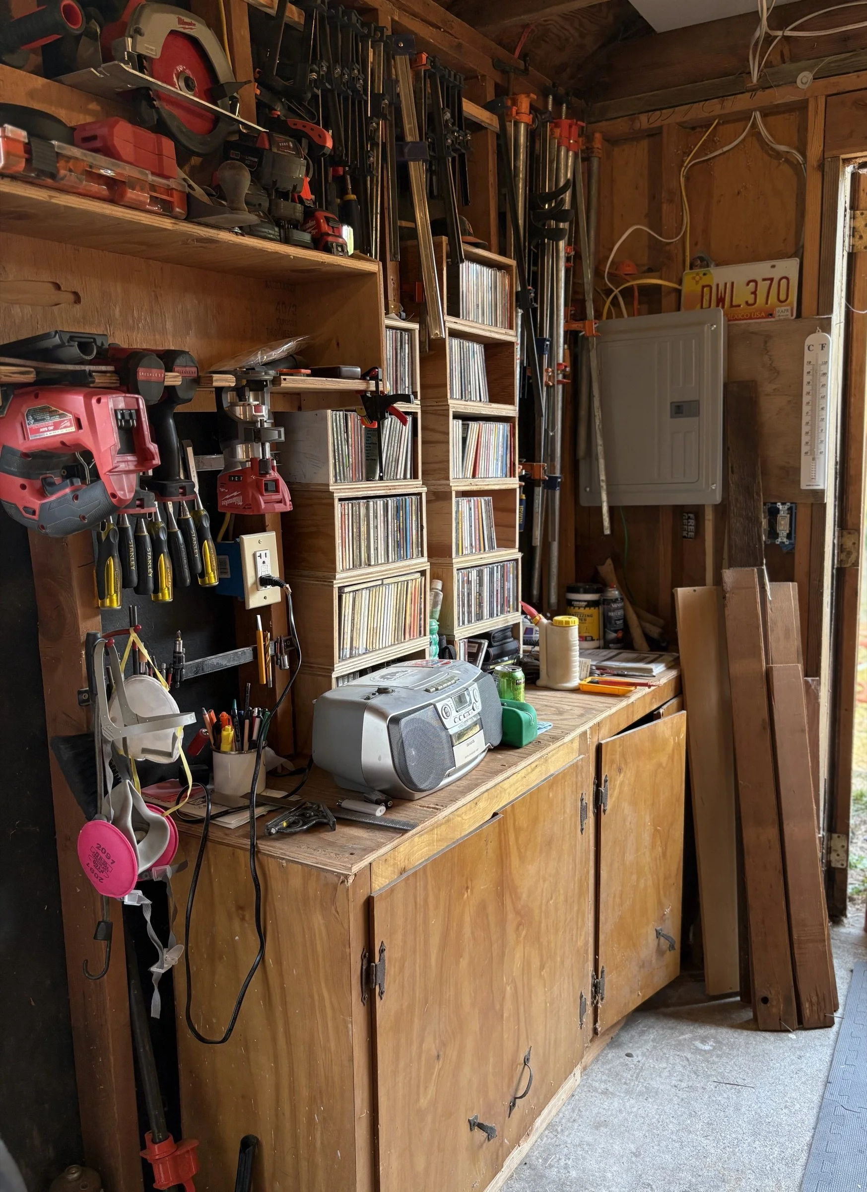 Workbench in a garage with tools, storage shelves, a stereo, and various equipment.