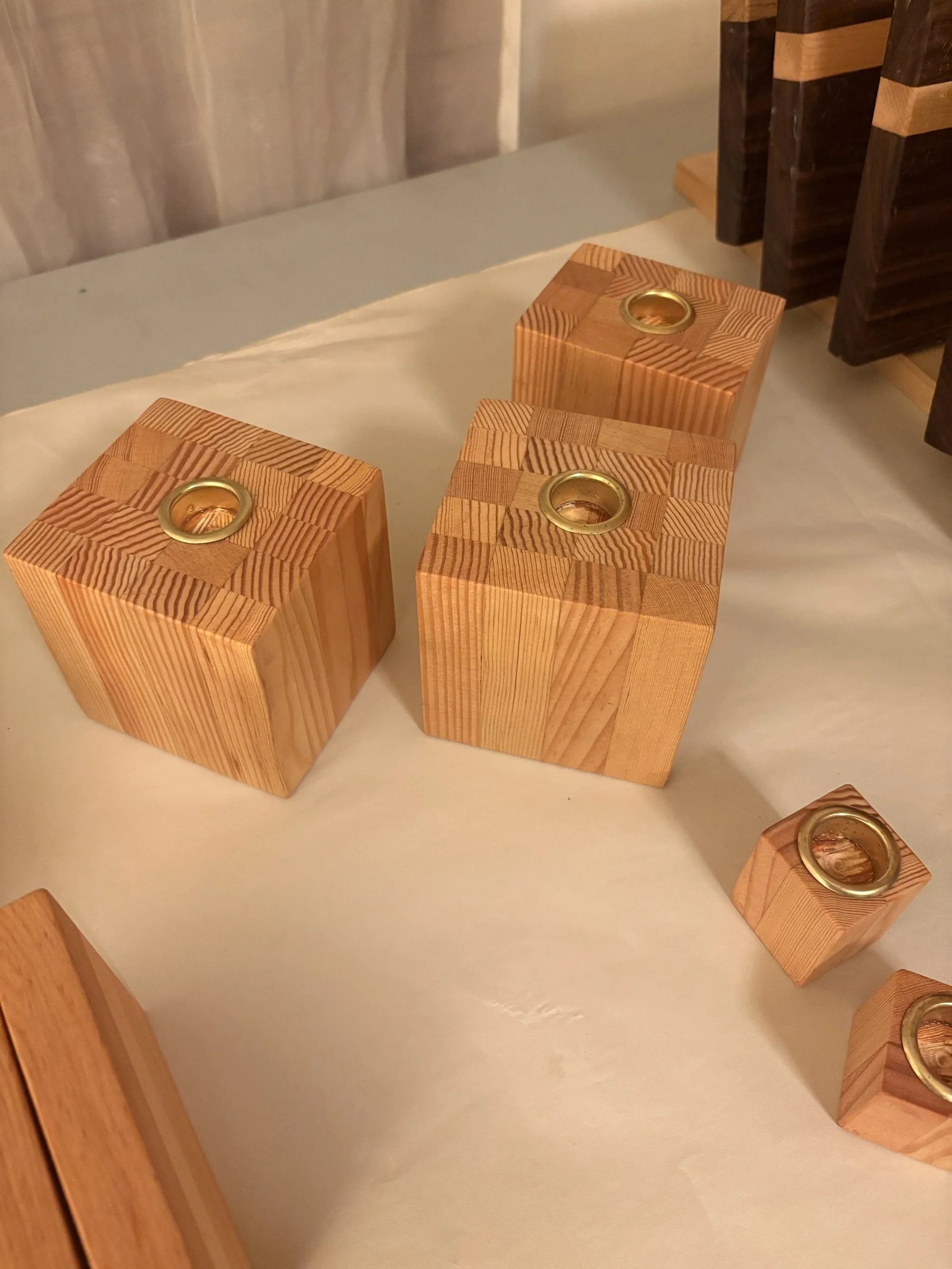 A set of five block candle holders in end-grain fir with brass candle cups.