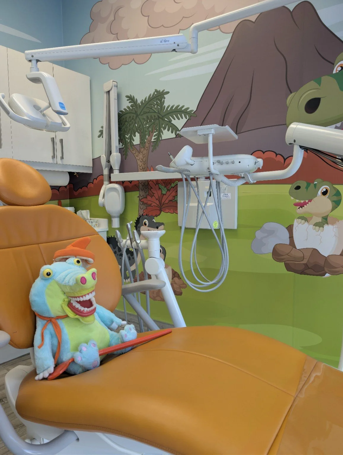 Children's treatment room at Fort Dental Clinic with a dinosaur mural.