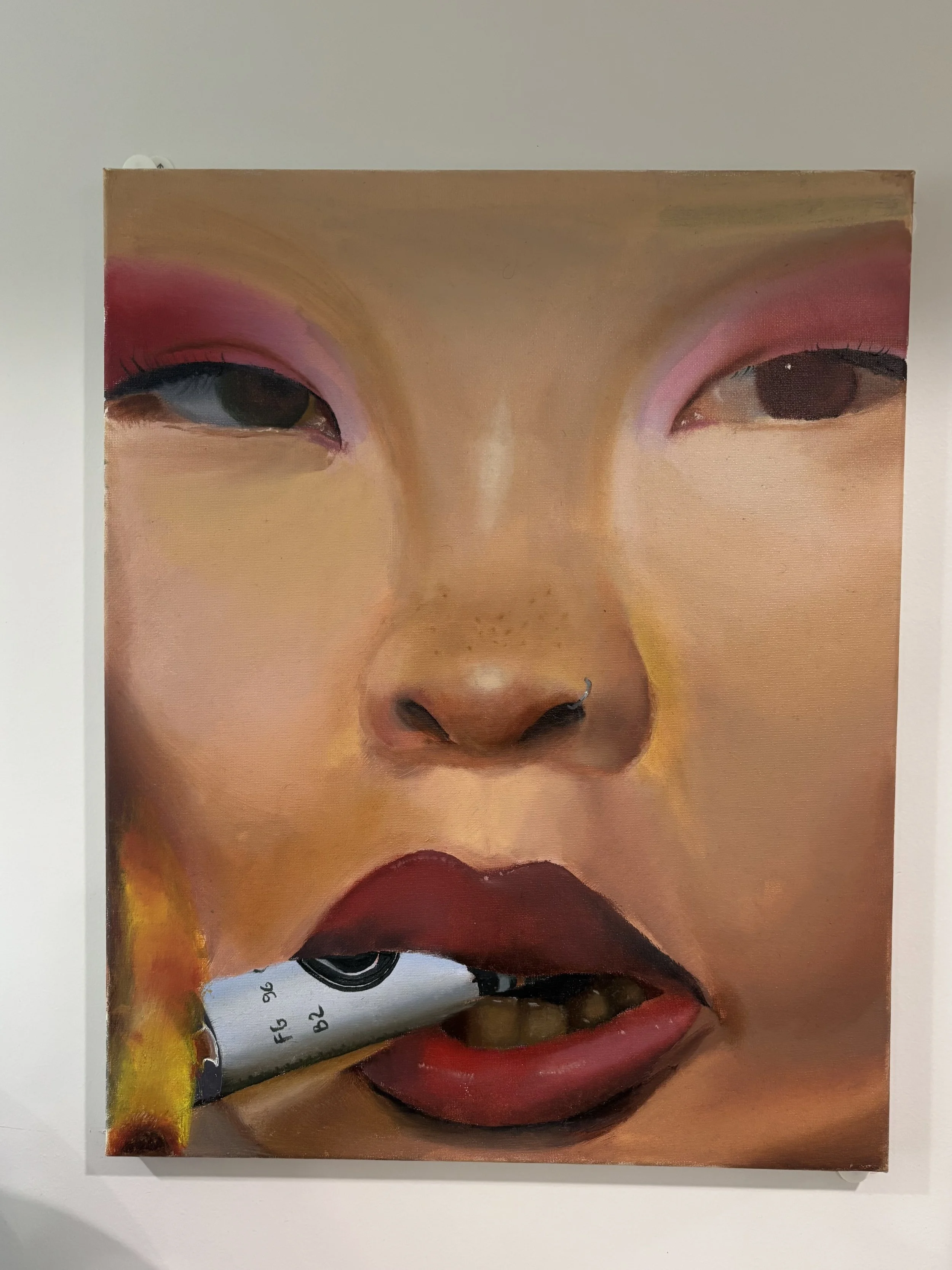 Close-up of a painting of a woman's face with pink eyeshadow, red lipstick, and a painted nose, with a cigarette in her mouth.