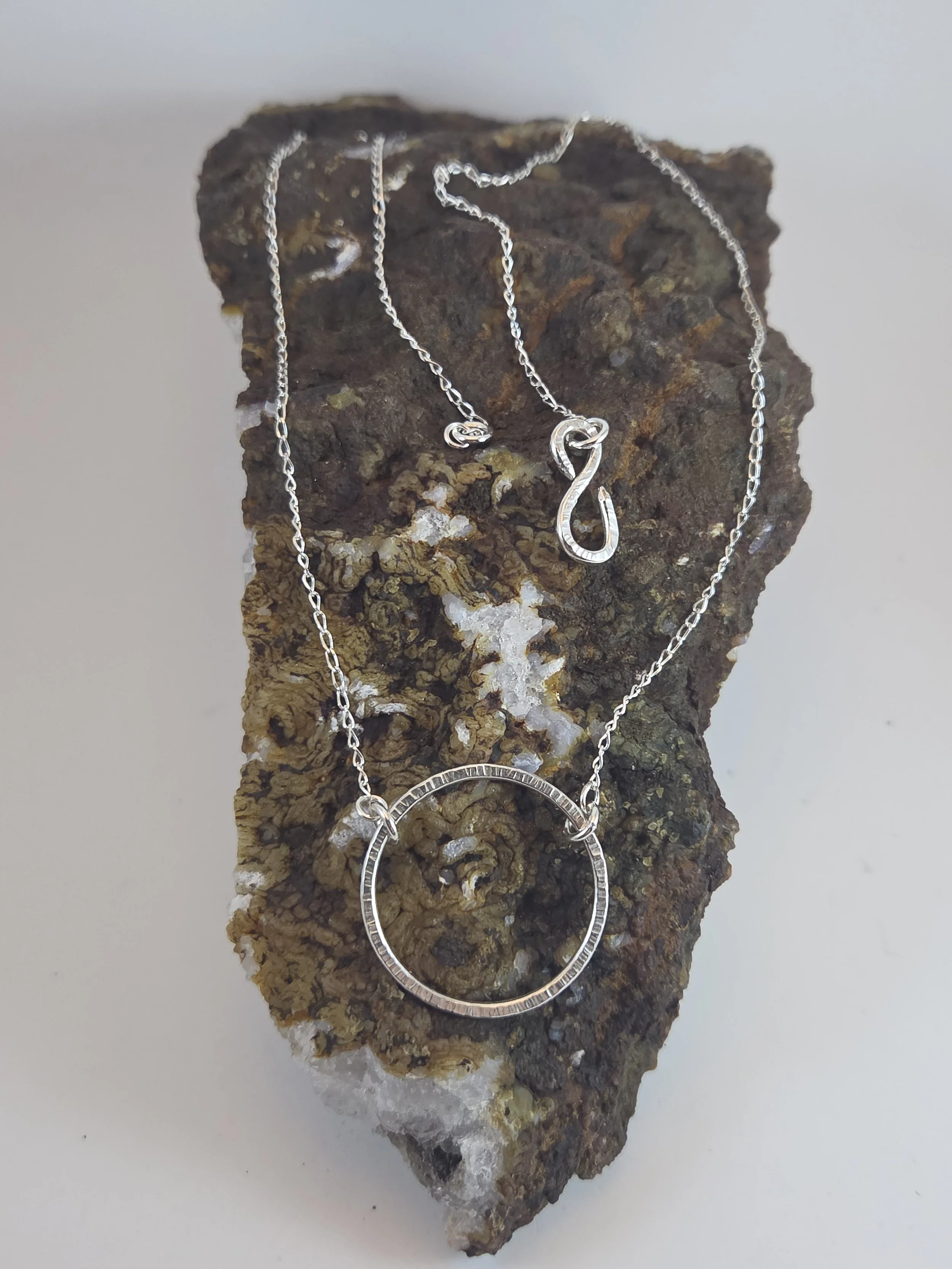 Silver necklace pendant draped on a crystal rock